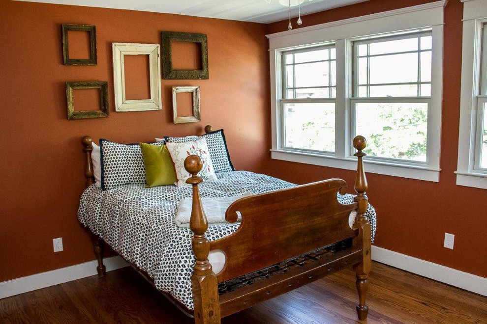 Esempio di una camera degli ospiti tradizionale di medie dimensioni con pareti arancioni e pavimento in legno massello medio