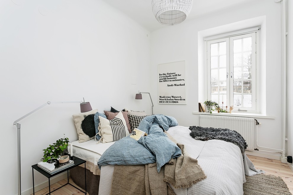 This is an example of a medium sized scandinavian master bedroom in Stockholm with white walls, light hardwood flooring and no fireplace.