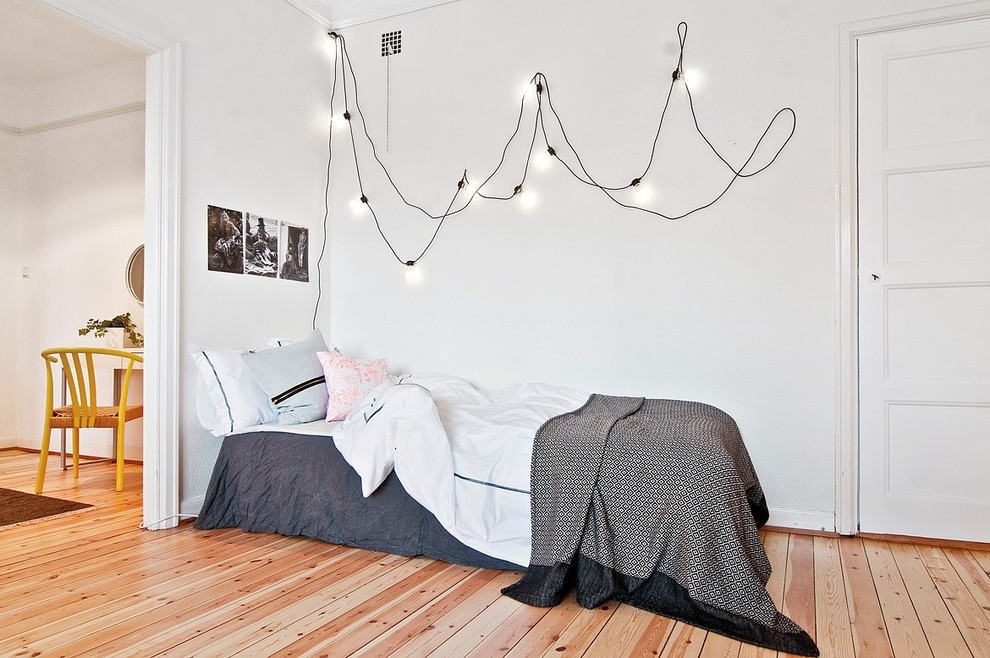 Diseño de habitación de invitados escandinava pequeña sin chimenea con paredes blancas y suelo de madera en tonos medios