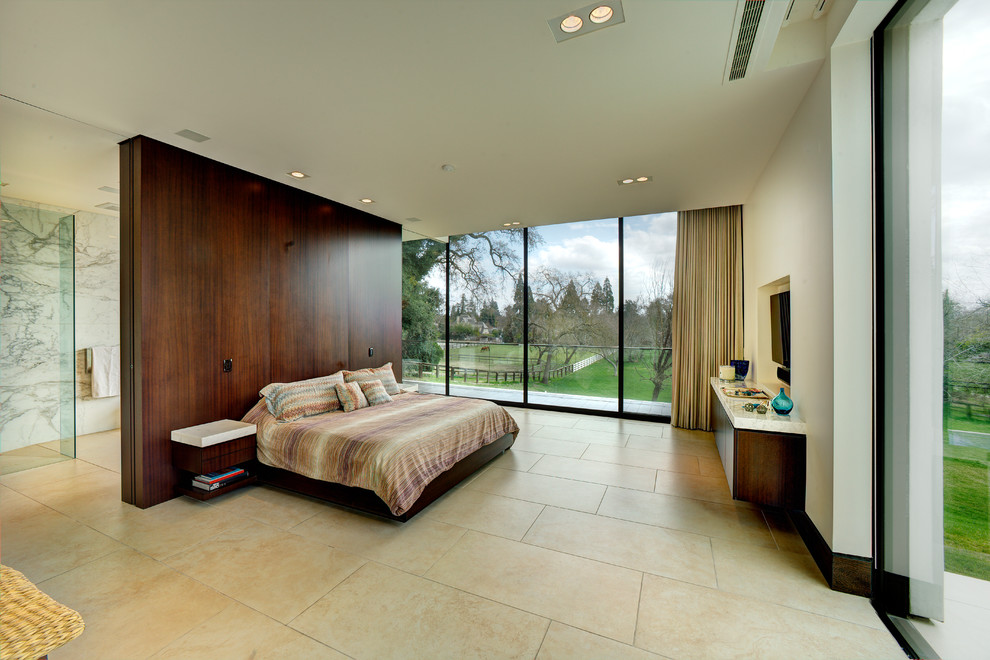 Cette image montre une grande chambre parentale minimaliste avec un mur blanc, un sol en calcaire, aucune cheminée et un sol beige.