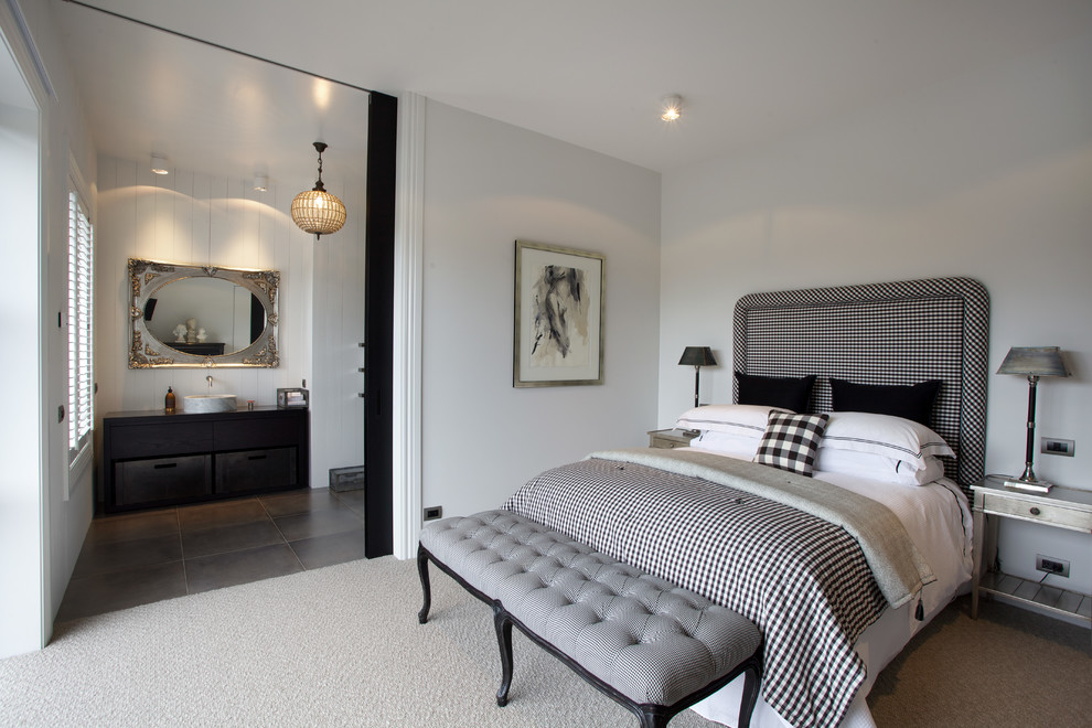 This is an example of a traditional master bedroom in Auckland with white walls and carpet.