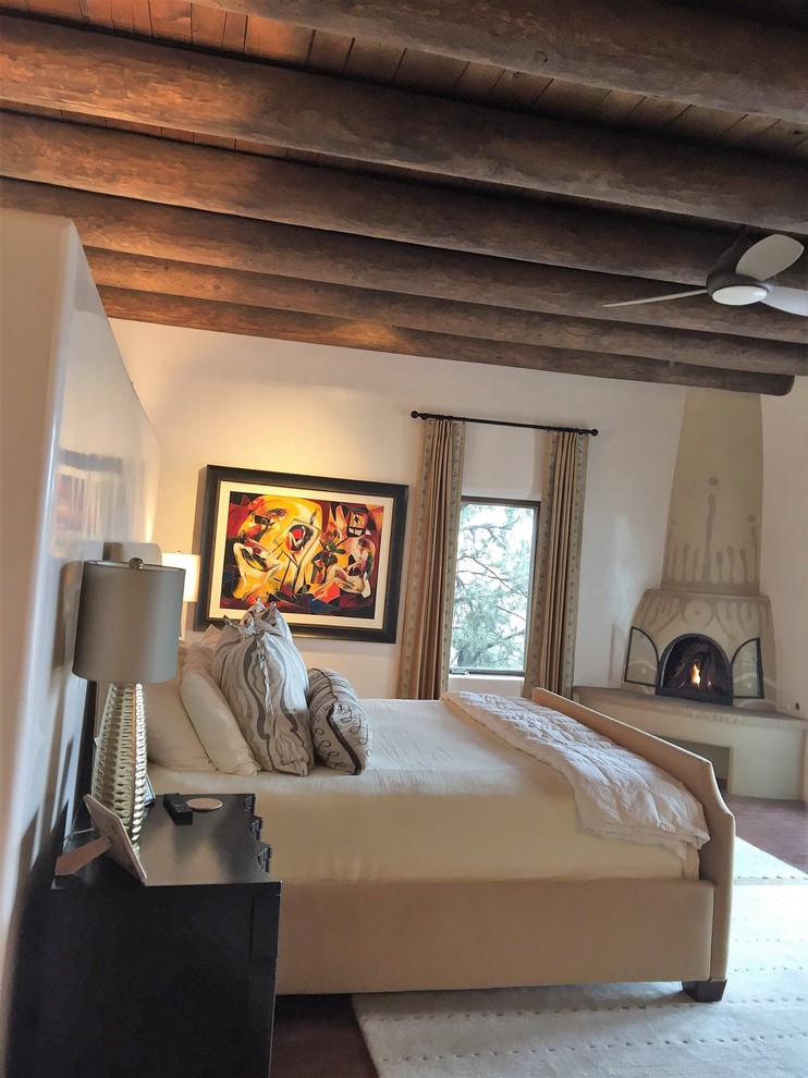 Modelo de dormitorio principal de estilo americano grande con paredes blancas, suelo de madera oscura, chimenea de esquina y suelo marrón