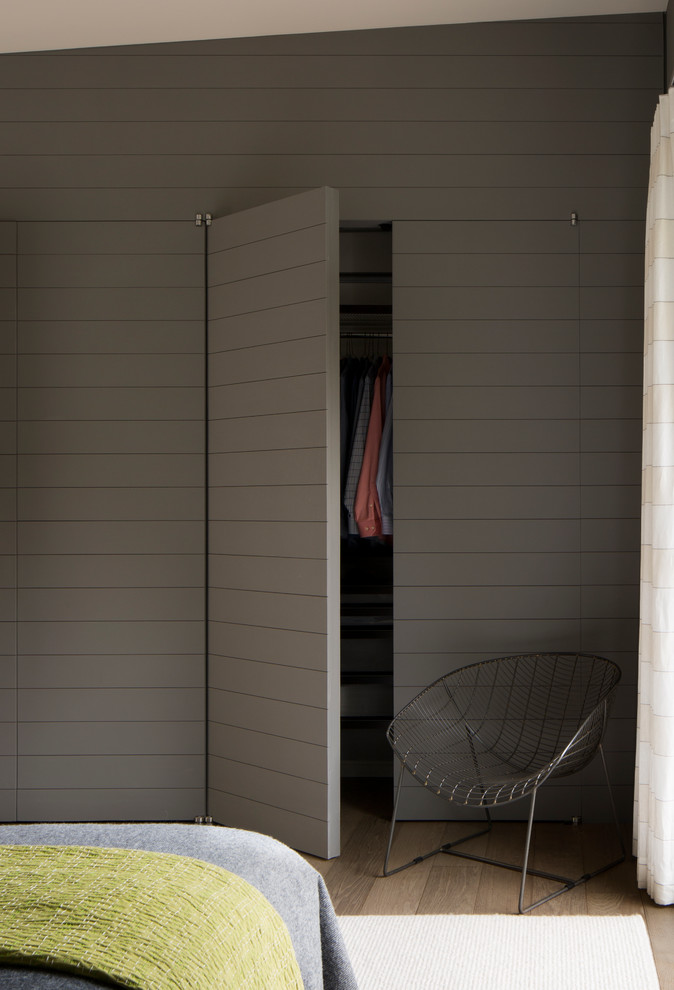 Réalisation d'une chambre parentale design avec un mur gris et un sol en bois brun.
