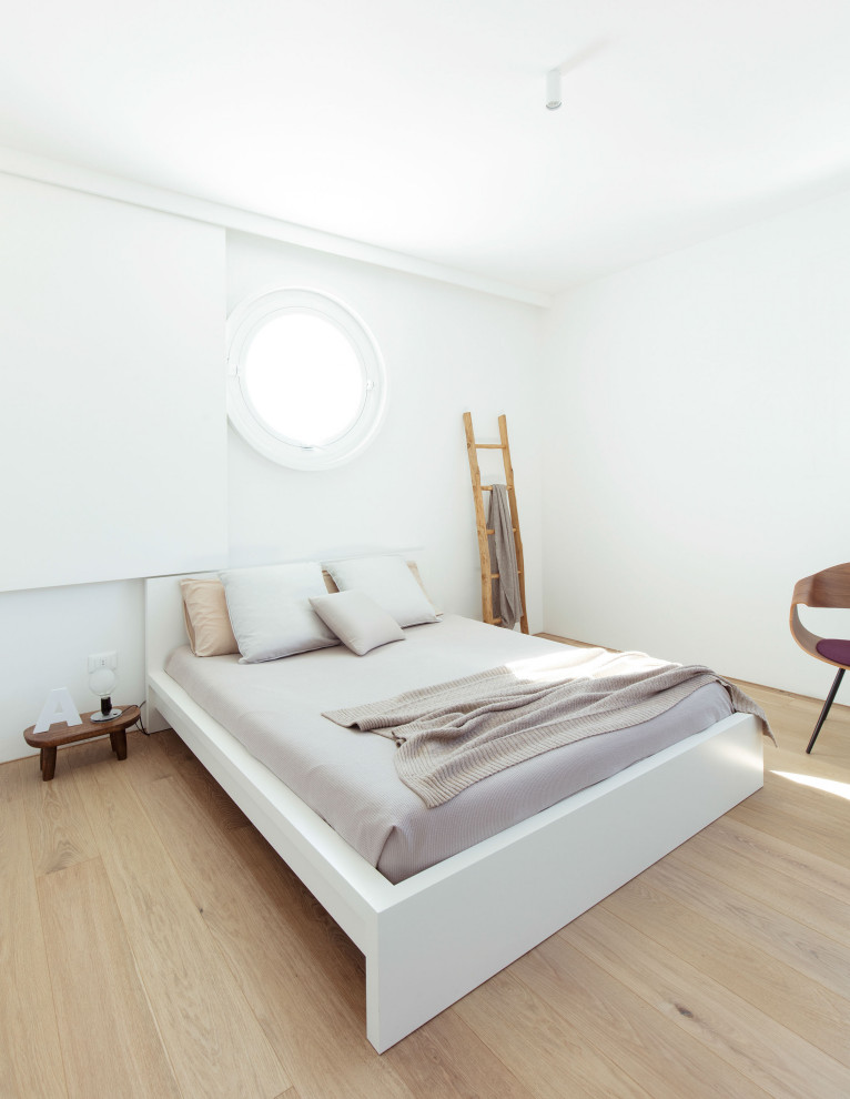 Immagine di una camera matrimoniale contemporanea di medie dimensioni con pareti bianche, pavimento in legno massello medio e pavimento marrone