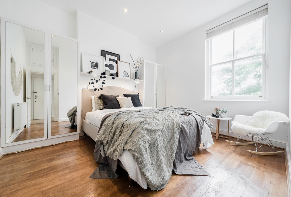 Bild på ett minimalistiskt sovrum, med vita väggar och ljust trägolv