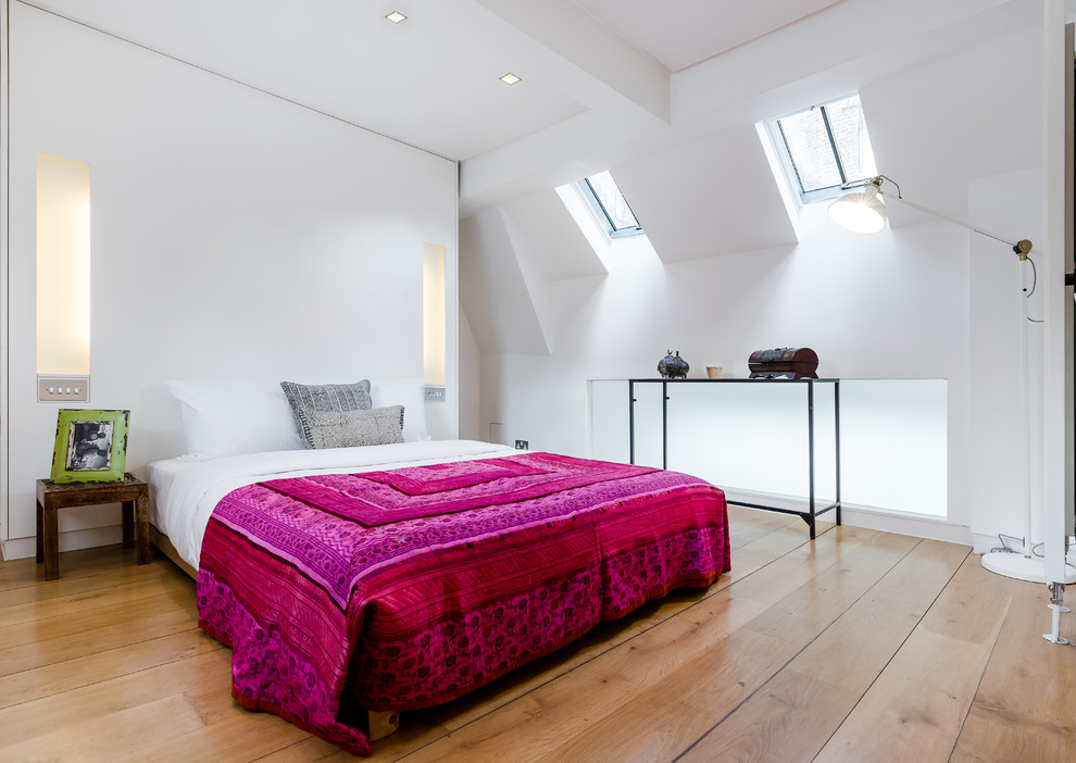 Mediterranean loft bedroom in London with white walls and light hardwood flooring.