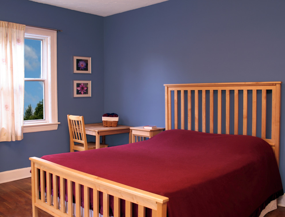 Cette photo montre une grande chambre d'amis moderne avec un mur bleu, un sol en bois brun et aucune cheminée.