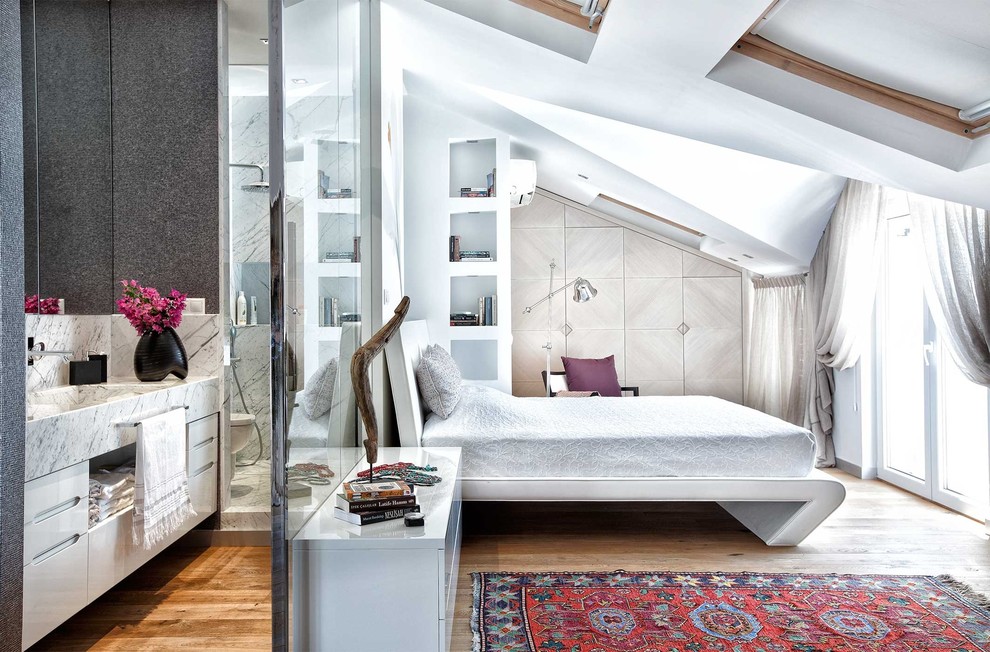 Modelo de dormitorio contemporáneo sin chimenea con paredes blancas y suelo de madera en tonos medios