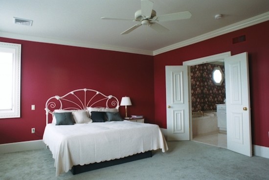 This is an example of a large bedroom in Other with red walls and carpet.