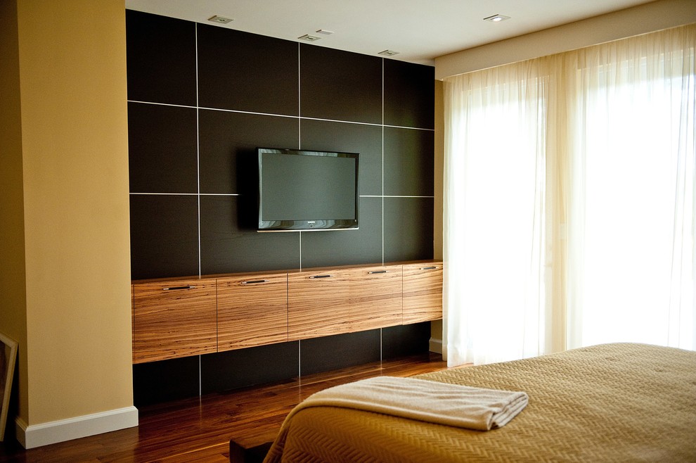 Пример оригинального дизайна: большая хозяйская спальня в современном стиле с желтыми стенами и темным паркетным полом без камина