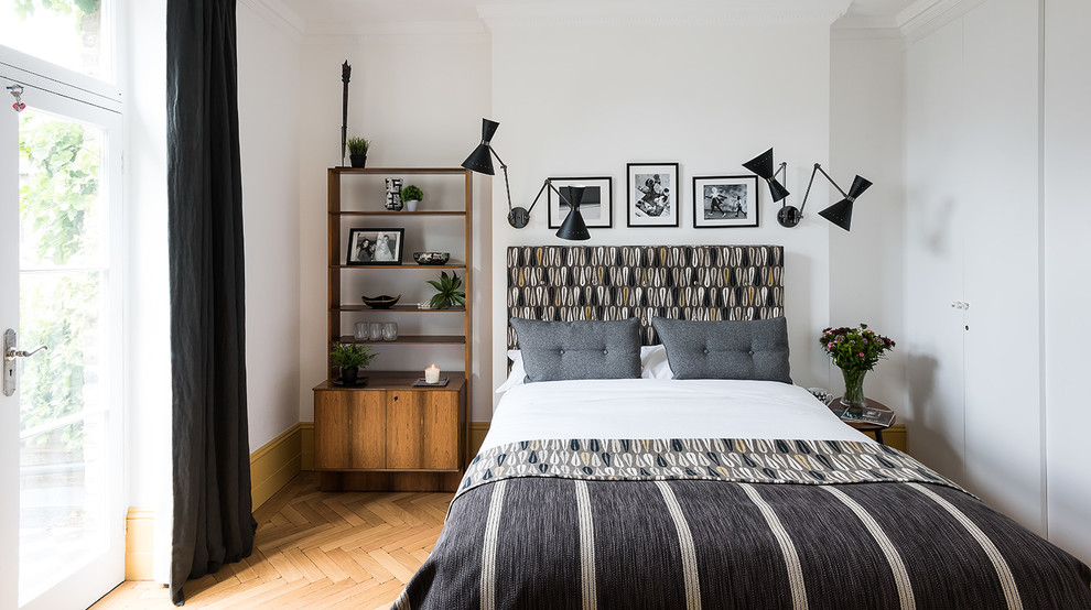 This is an example of a scandinavian bedroom in London with white walls and medium hardwood flooring.