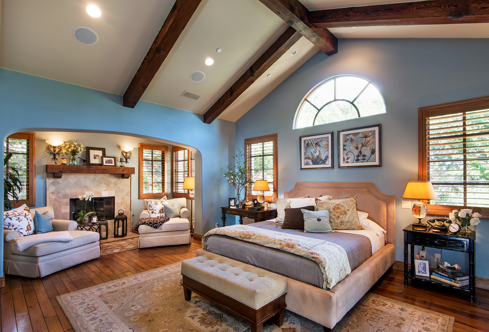 Mediterranes Schlafzimmer mit blauer Wandfarbe, braunem Holzboden, gefliester Kaminumrandung und Kamin in San Francisco
