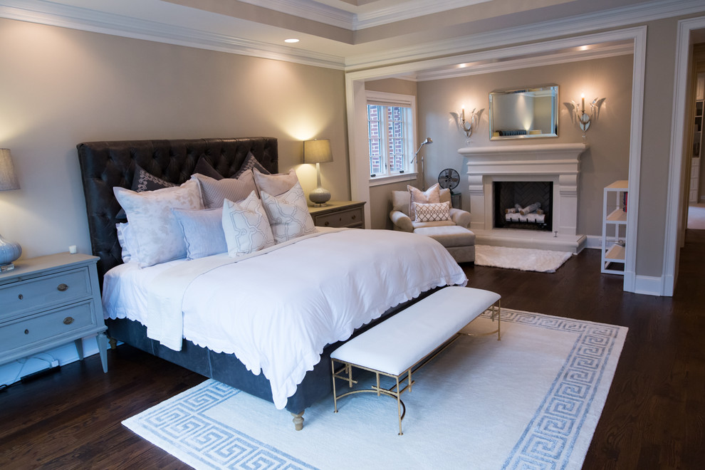 Diseño de dormitorio principal clásico renovado grande con paredes beige, suelo de madera en tonos medios, todas las chimeneas y marco de chimenea de madera