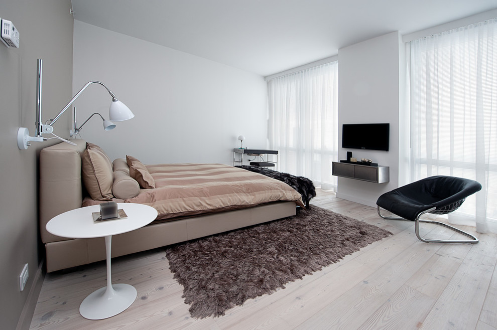Diseño de dormitorio principal contemporáneo de tamaño medio sin chimenea con paredes blancas, suelo de madera clara y suelo beige