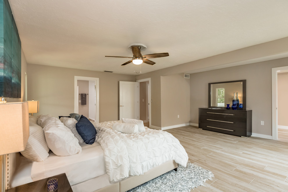 Modelo de dormitorio principal minimalista grande con paredes grises, suelo de baldosas de porcelana y suelo beige