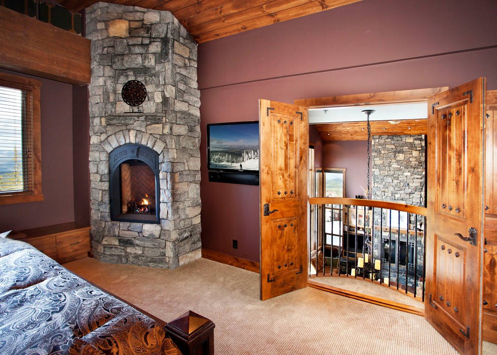 Bedroom - rustic master carpeted bedroom idea in Vancouver with red walls, a corner fireplace and a stone fireplace