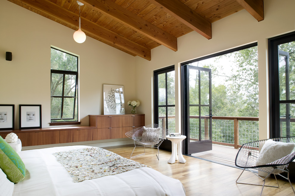 Diseño de dormitorio principal actual grande sin chimenea con paredes beige y suelo de madera clara