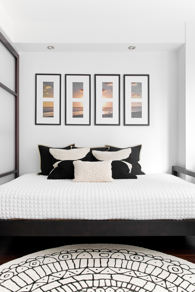 Idée de décoration pour une petite chambre d'amis design avec un mur blanc, parquet foncé et un sol marron.