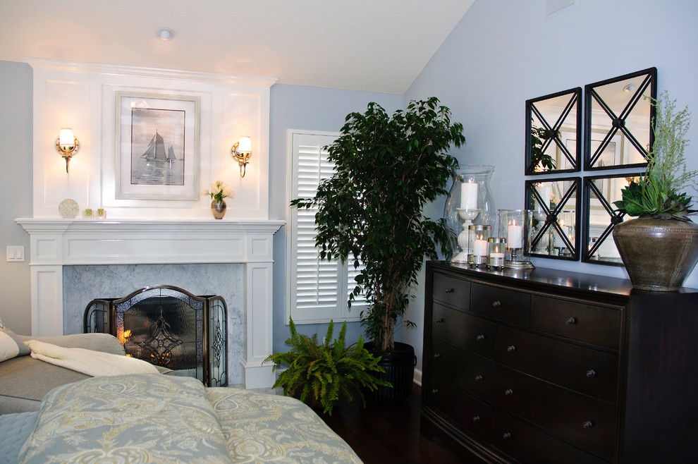 Cette image montre une chambre parentale traditionnelle de taille moyenne avec un mur bleu, parquet foncé, un sol marron, une cheminée standard et un manteau de cheminée en bois.