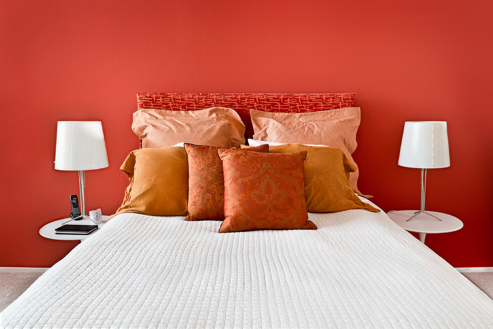 Imagen de dormitorio principal contemporáneo pequeño sin chimenea con paredes rojas y moqueta
