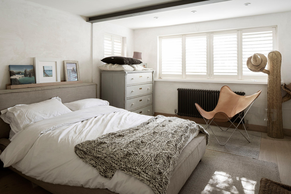 Ejemplo de habitación de invitados costera de tamaño medio sin chimenea con paredes beige y suelo de madera clara