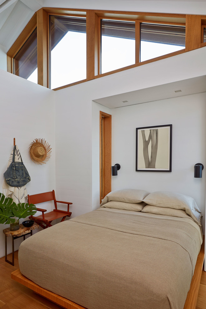 Foto di una camera degli ospiti stile marino di medie dimensioni con pareti bianche, pavimento in legno massello medio, nessun camino e pavimento marrone