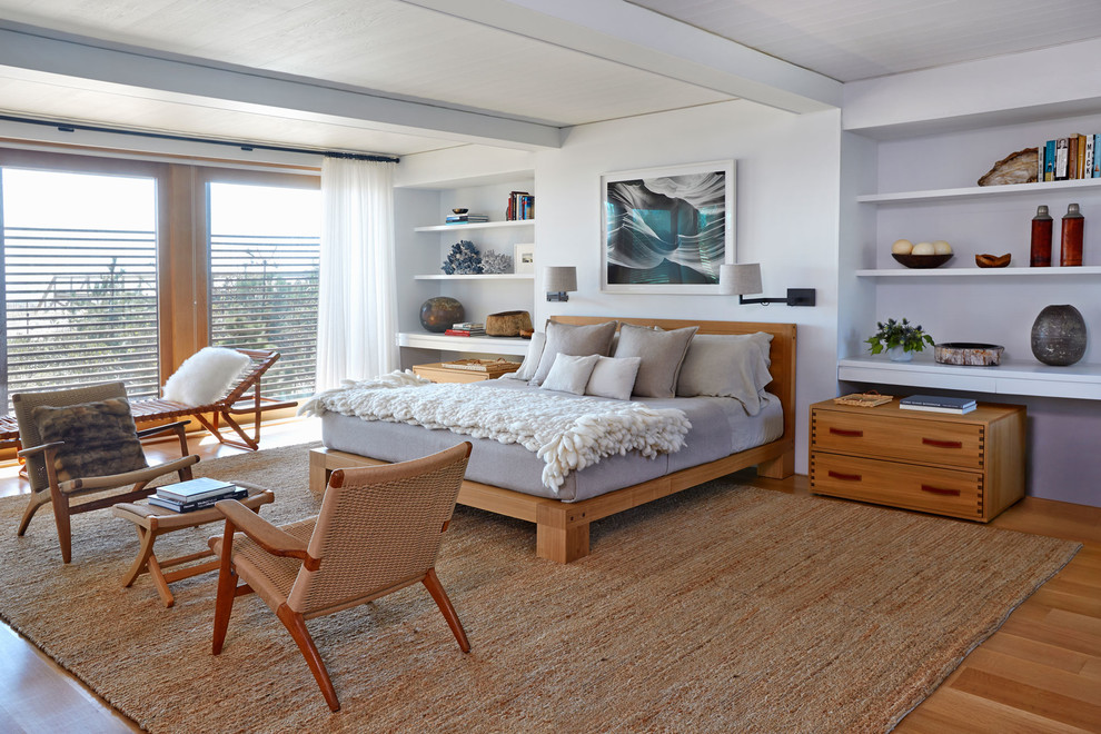Imagen de dormitorio principal marinero grande sin chimenea con paredes blancas, suelo de madera en tonos medios y suelo marrón