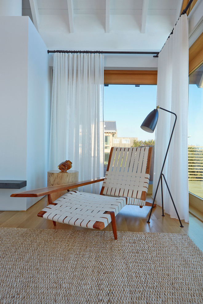 Immagine di una camera degli ospiti costiera di medie dimensioni con pareti bianche, pavimento in legno massello medio, camino classico e pavimento marrone