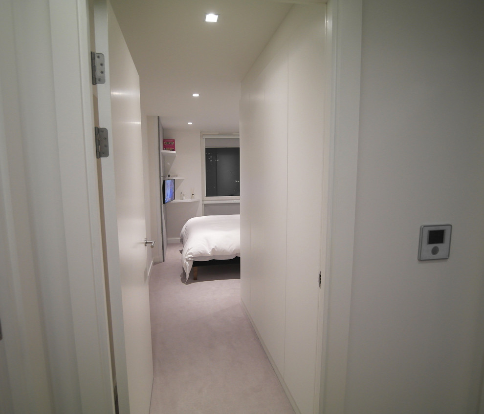 Immagine di una camera degli ospiti minimal di medie dimensioni con pareti bianche, moquette e nessun camino