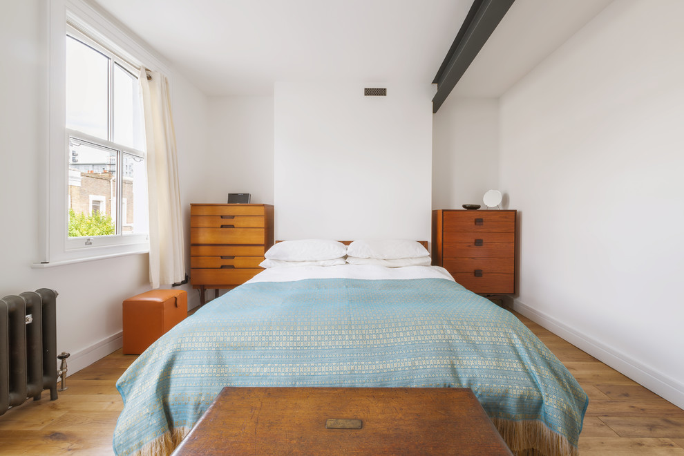 ロンドンにある中くらいなコンテンポラリースタイルのおしゃれな主寝室 (白い壁、無垢フローリング、暖炉なし、漆喰の暖炉まわり、茶色い床) のレイアウト