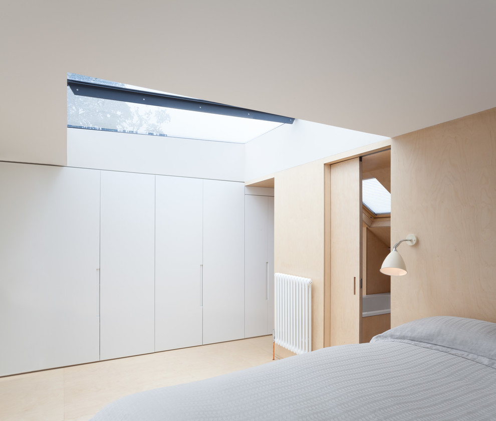 Small contemporary master bedroom in London with white walls, plywood flooring and no fireplace.