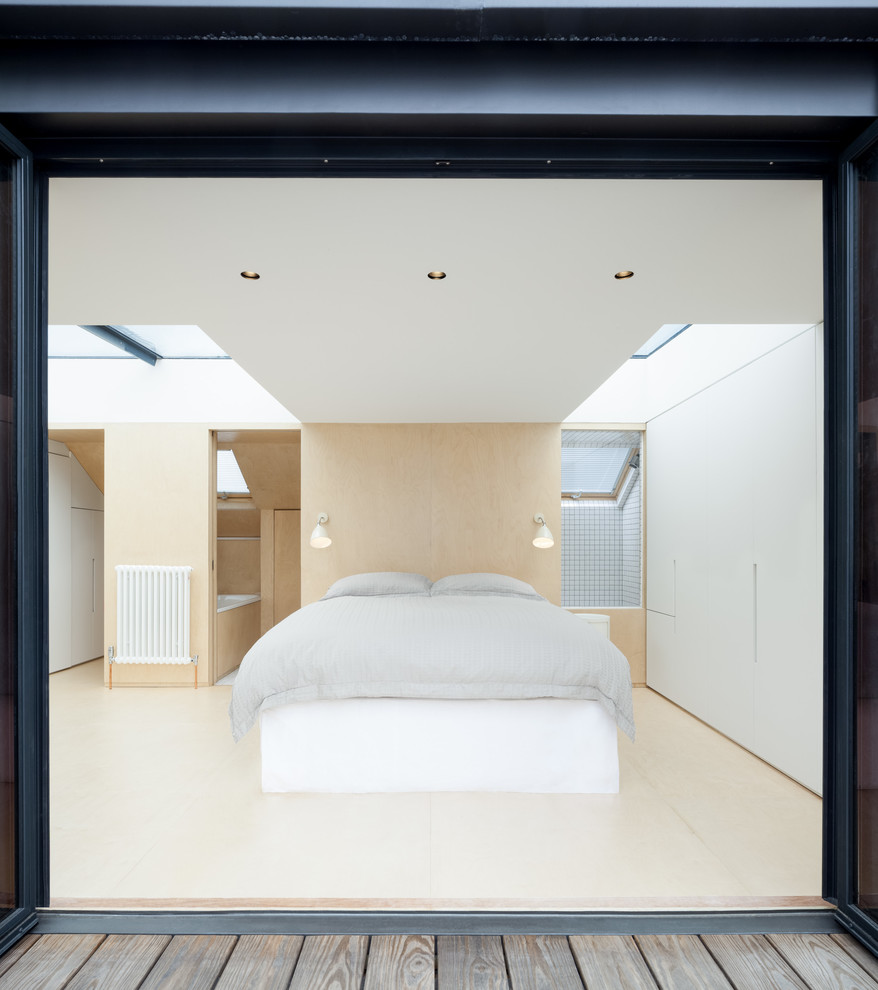 Imagen de dormitorio principal contemporáneo pequeño sin chimenea con paredes blancas y suelo de contrachapado