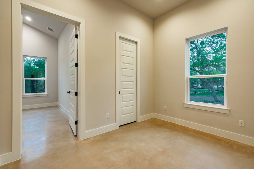 Ejemplo de dormitorio principal campestre de tamaño medio sin chimenea con paredes beige, suelo de cemento y suelo gris