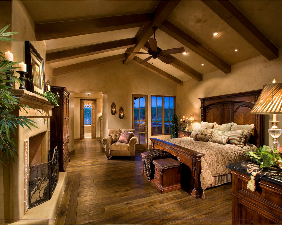 Mediterranes Schlafzimmer mit beiger Wandfarbe, dunklem Holzboden und Kamin in Phoenix