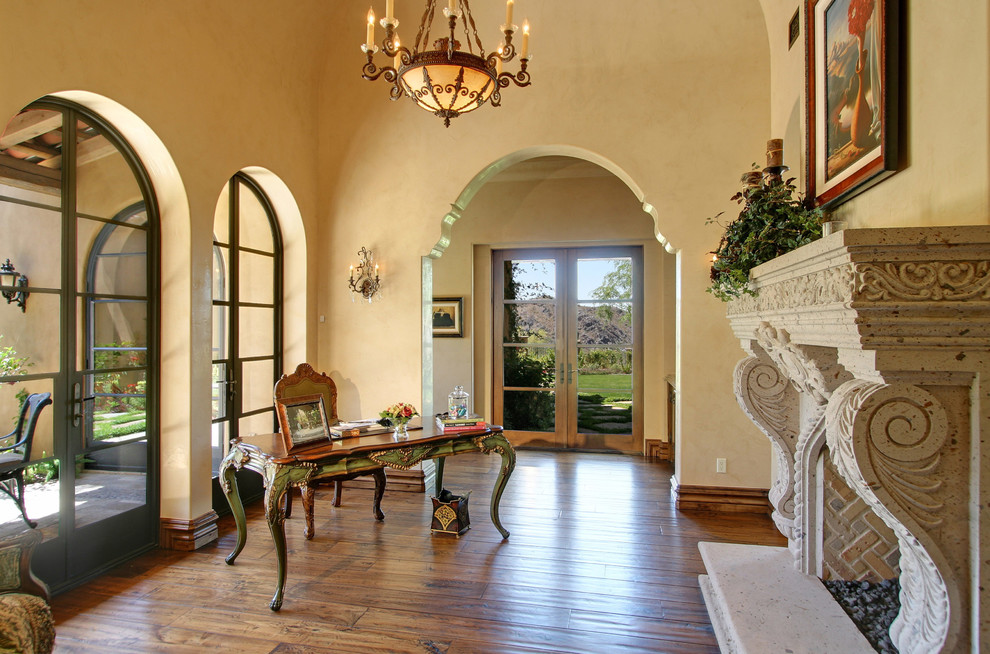 Geräumiges Mediterranes Hauptschlafzimmer mit beiger Wandfarbe, braunem Holzboden, Tunnelkamin und Kaminumrandung aus Stein in Phoenix
