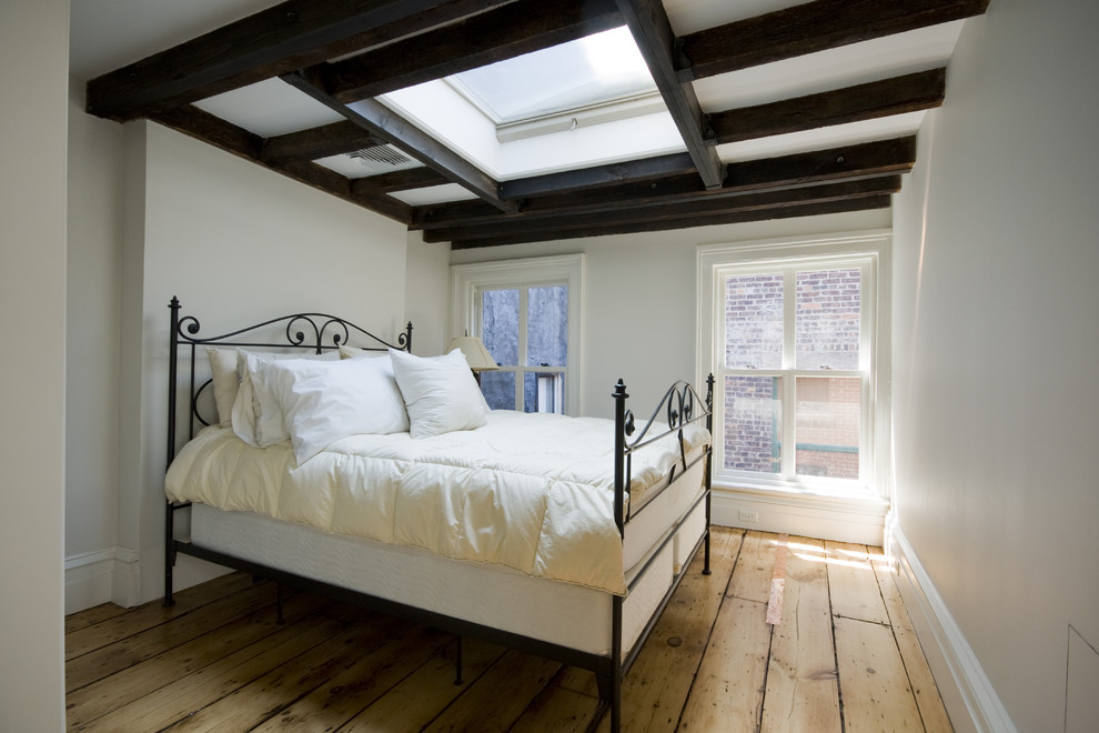 Foto de habitación de invitados tradicional sin chimenea con paredes blancas y suelo de madera clara