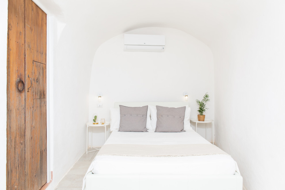 Esempio di una camera da letto mediterranea con pareti bianche e pavimento grigio