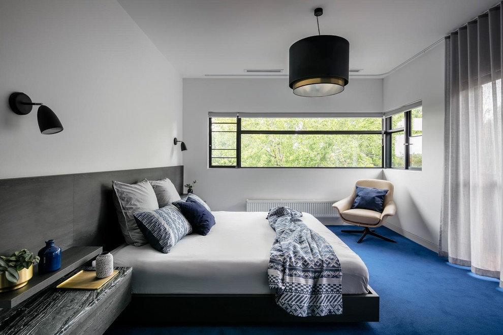 Idéer för ett modernt sovrum, med vita väggar, heltäckningsmatta och blått golv