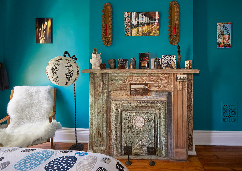 Exemple d'une chambre parentale éclectique de taille moyenne avec un mur bleu, un sol en bois brun, cheminée suspendue et un manteau de cheminée en métal.