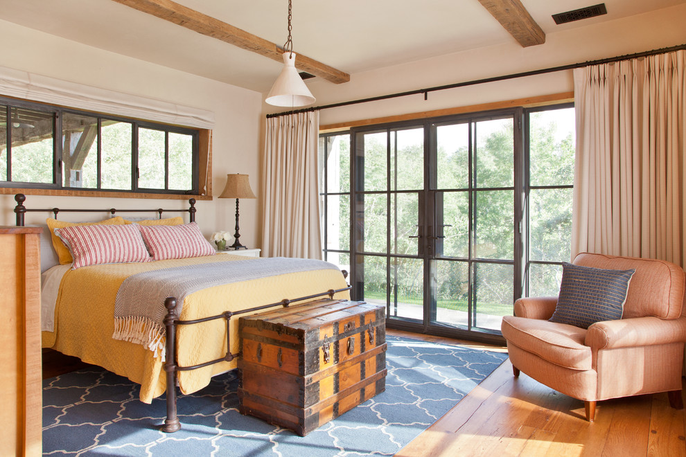 Uriges Hauptschlafzimmer mit weißer Wandfarbe, braunem Holzboden und orangem Boden in Sonstige