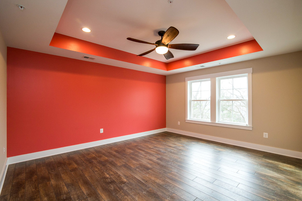 Ejemplo de dormitorio principal de estilo americano con paredes rojas y suelo de madera en tonos medios