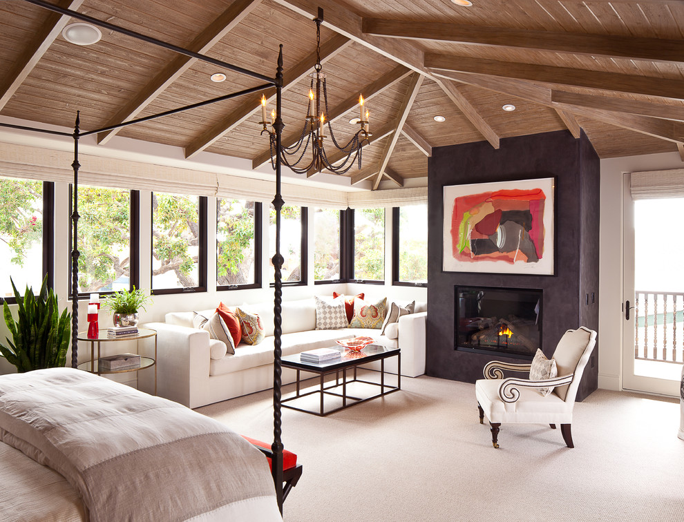 Example of a large tuscan master carpeted bedroom design in Orange County with a plaster fireplace, white walls and a standard fireplace