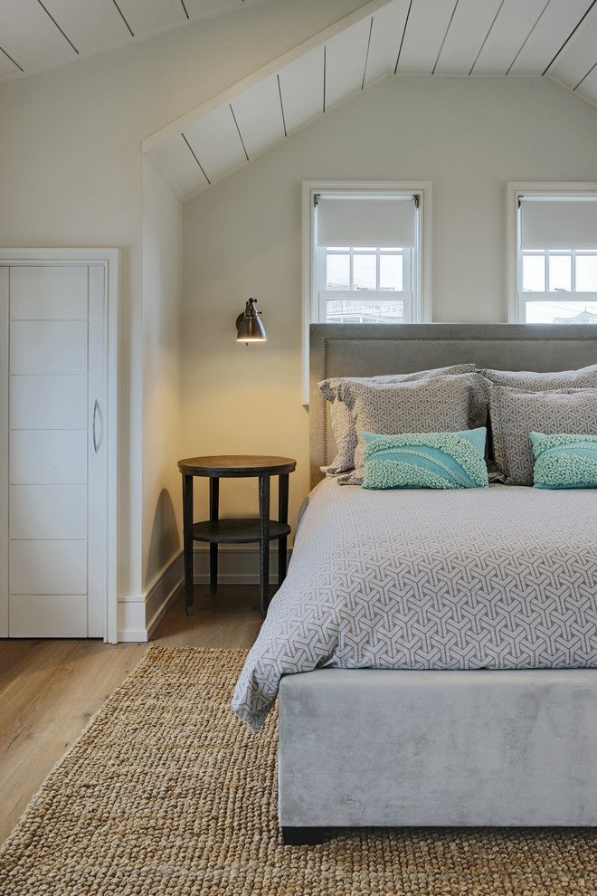 This is an example of a coastal bedroom in Other with beige walls and light hardwood flooring.