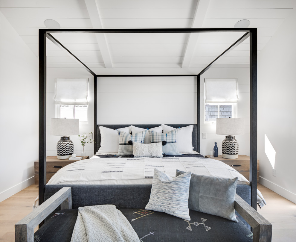 Ejemplo de dormitorio principal costero grande sin chimenea con paredes blancas, suelo de madera clara y suelo beige