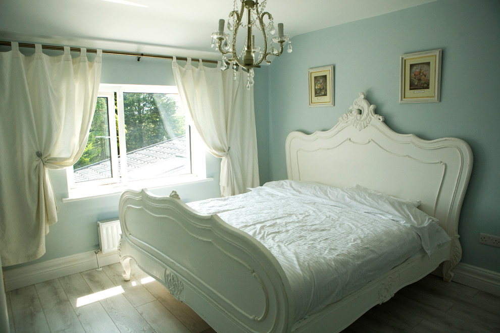 Modelo de dormitorio principal clásico de tamaño medio con paredes azules y suelo de madera clara