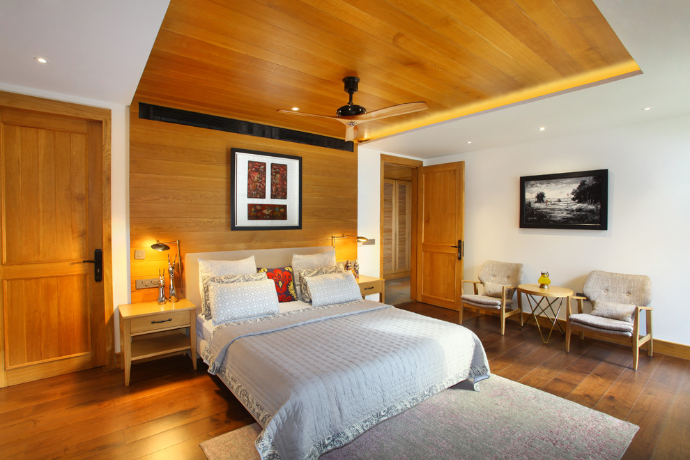 Bild på ett funkis sovrum, med vita väggar, mellanmörkt trägolv och brunt golv