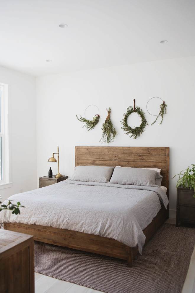Foto på ett mellanstort lantligt sovrum, med vita väggar och ljust trägolv