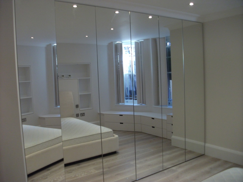 Photo of a medium sized contemporary master bedroom in London with light hardwood flooring, no fireplace, beige walls and beige floors.