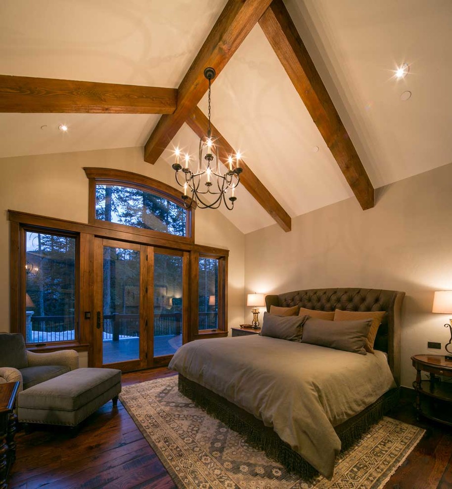 Aménagement d'une chambre parentale montagne de taille moyenne avec un mur beige, un sol en bois brun et un manteau de cheminée en pierre.
