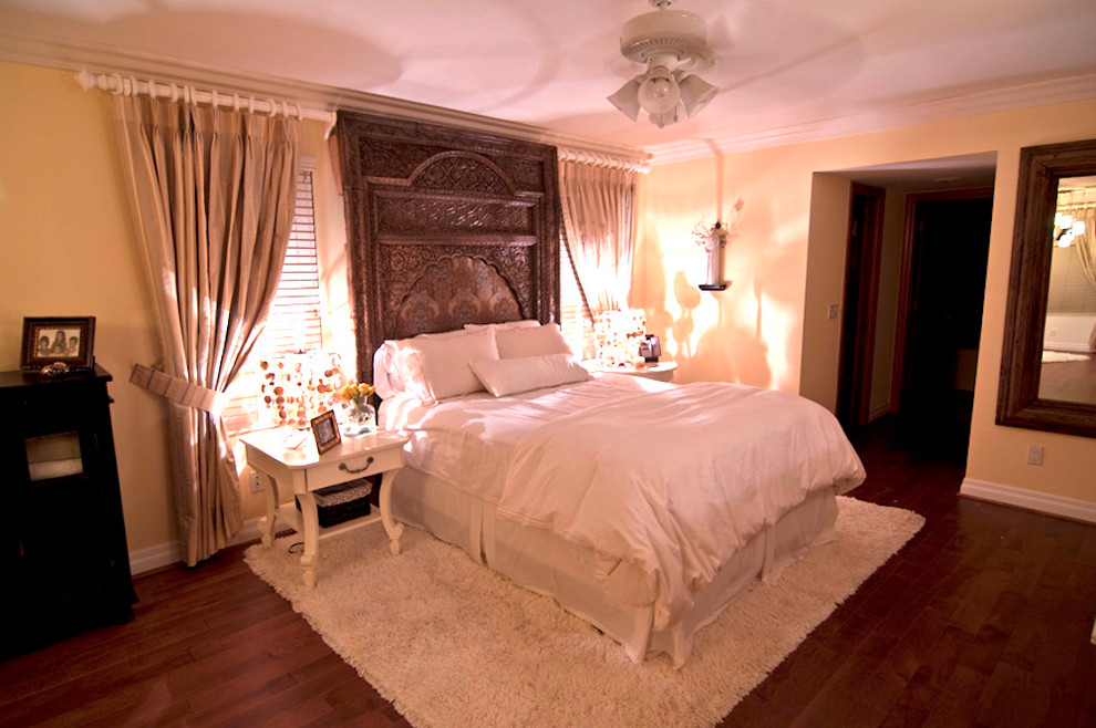Foto de dormitorio principal clásico renovado grande sin chimenea con paredes amarillas y suelo de madera en tonos medios